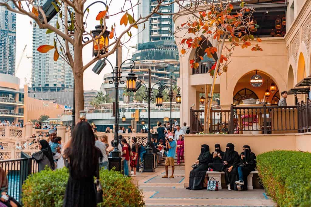 Vibrant outdoor scene in Dubai with people enjoying leisure time and modern architecture.